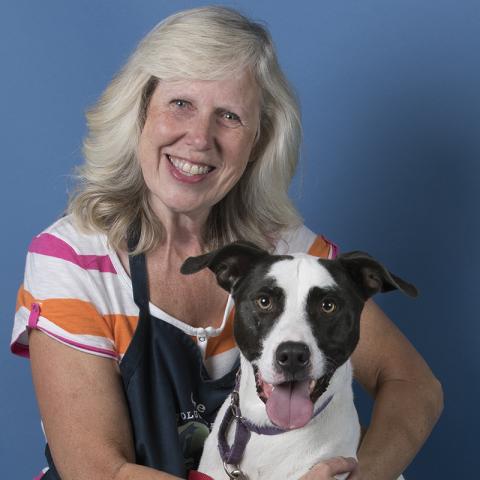 Woman standing behind a pit mix dog, her arms wrapped around his chest